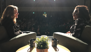 Author and interviewer on lit stage in front of the auditorium