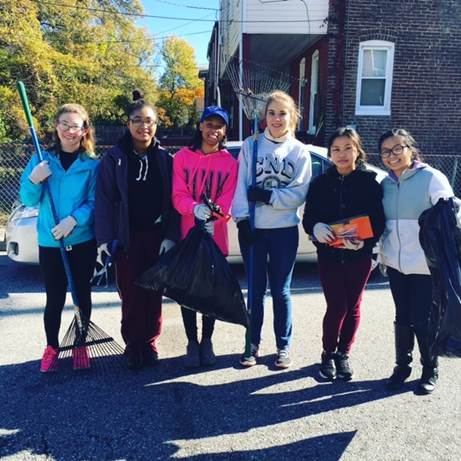 Students holding trash bags and rakes