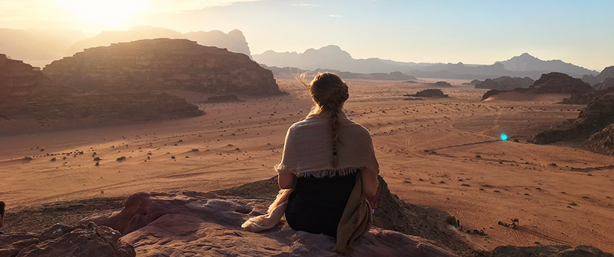 Women sitting on a mountain overlooking a desert at sunset
