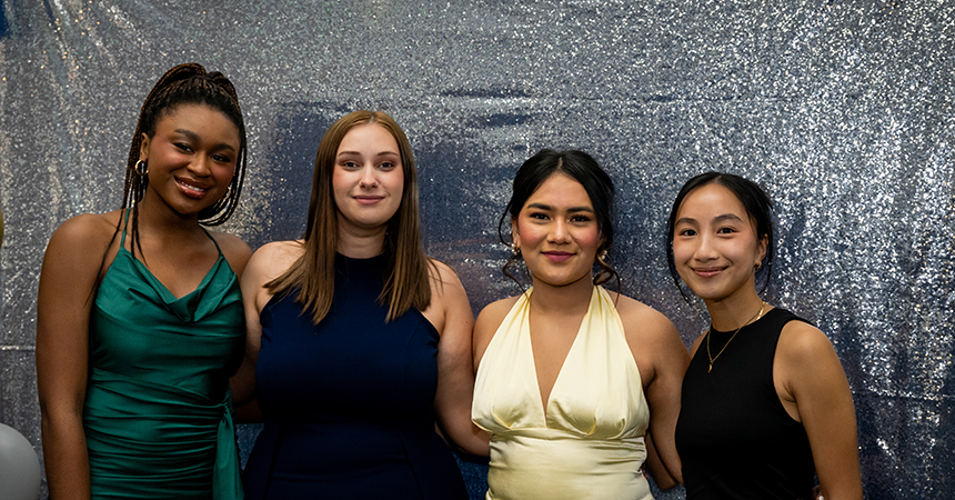 Four women dressed in cocktail dresses pose for the picture