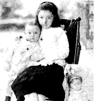 Old photo of a young girl sitting with a baby