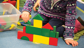 Hands of a child building a block castle