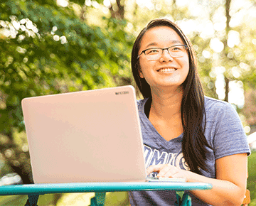 Student with a laptop outside on a sunny day