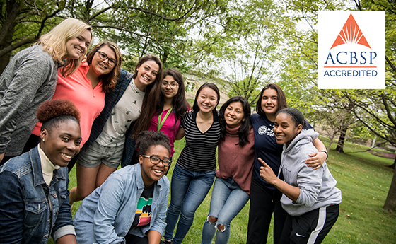 group shot of a business class outside on campus with accreditation logo overlayed