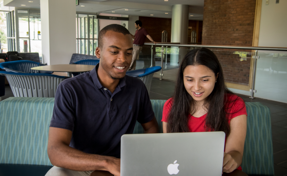 two students sitting down looking at a laptop