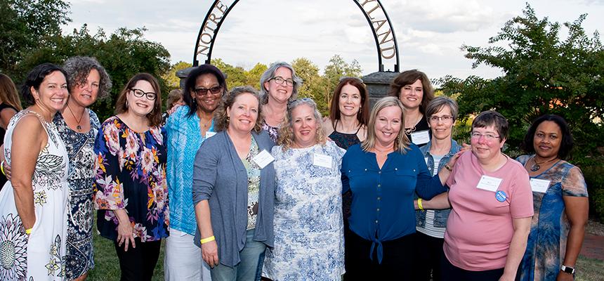 large group of alumnae at Reunion 2019, standing in front of NDMU archway