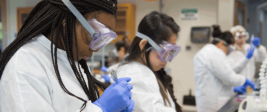 Students in lab coats and goggles in a lab