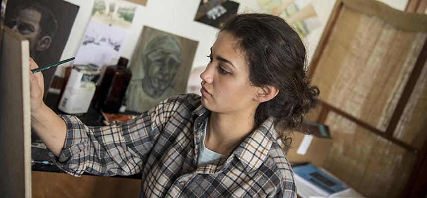 Student sitting at easel painting