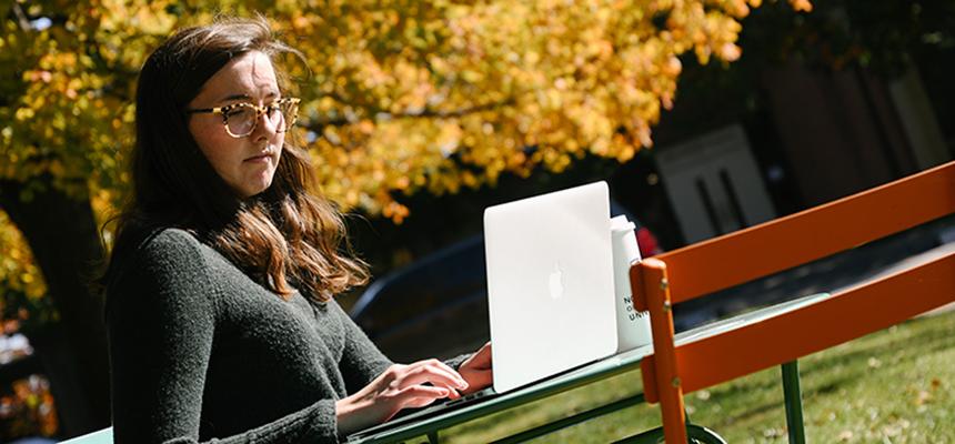 student sitting with laptop outside