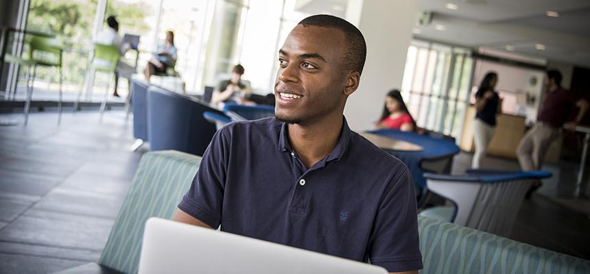 male student sitting in library at computer