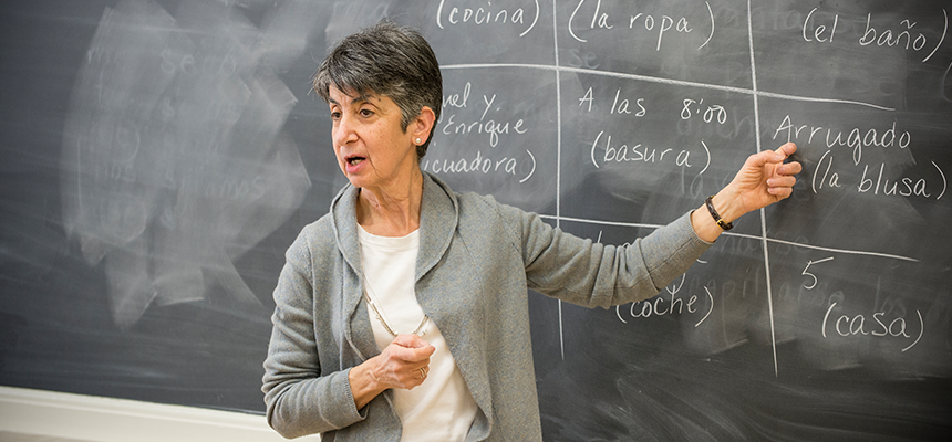 teacher standing in front of blackboard with spanish words