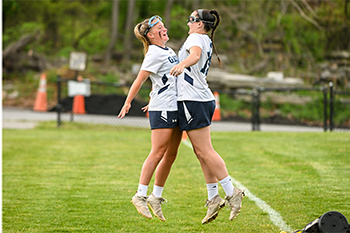 Two Lacrosse students chest bumping